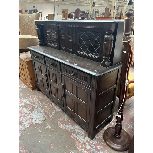 82 - A carved oak court cupboard with two upper leaded glass doors, three drawers and three cupboard door... 