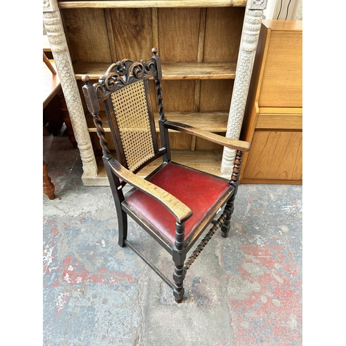 170 - An early 20th century carved oak armchair with rattan back and red leatherette upholstery