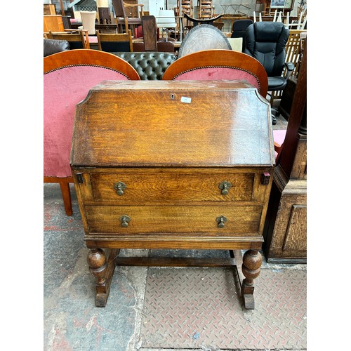 175 - A 1930s oak bureau with two drawers, fall front and baluster supports