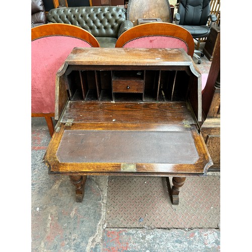 175 - A 1930s oak bureau with two drawers, fall front and baluster supports