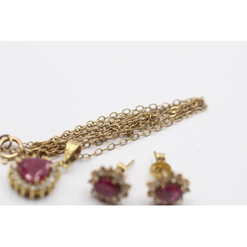 2051 - A 9ct gold ruby and clear gemstone halo pendant necklace and earrings set - approx. gross weight 4.3... 