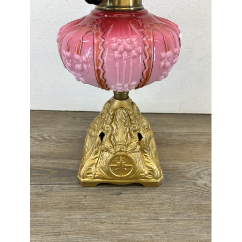 410 - A late 19th/early 20th century A. L. C. gilt metal and pink glass oil lamp with clear glass funnel -... 