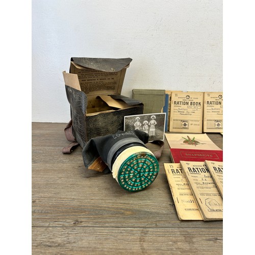 404 - A collection of militaria to include two gas masks, Ministry of Food ration books etc.