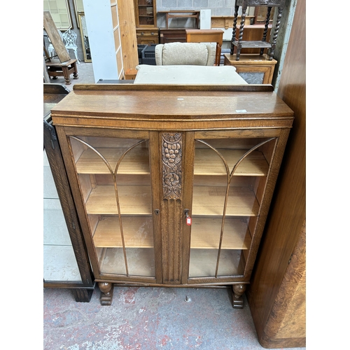 106 - A carved oak bookcase with two glazed doors, four internal shelves and baluster supports (key in off... 