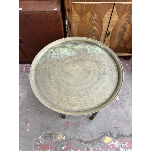 135 - A Middle Eastern wooden collapsible travel table with brass circular tray - approx. 57cm diameter