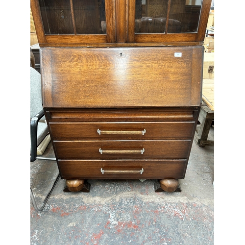 148 - An Art Deco style oak bureau bookcase with two upper glazed doors, fall front, three drawers and bal... 