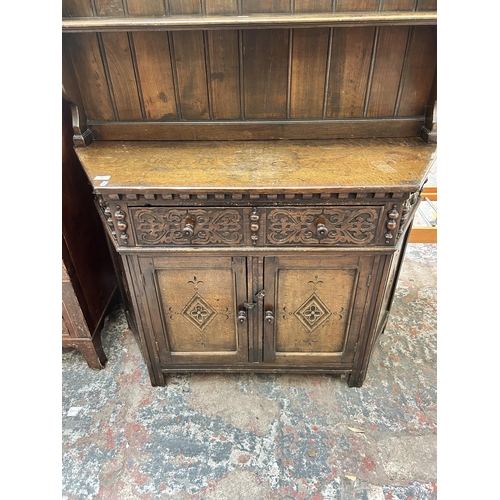 16 - A 17th century style carved oak dresser with upper plate rack, single drawer and two lower cupboard ... 