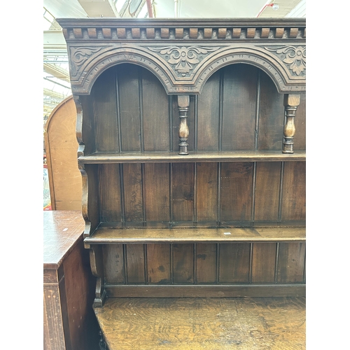 16 - A 17th century style carved oak dresser with upper plate rack, single drawer and two lower cupboard ... 