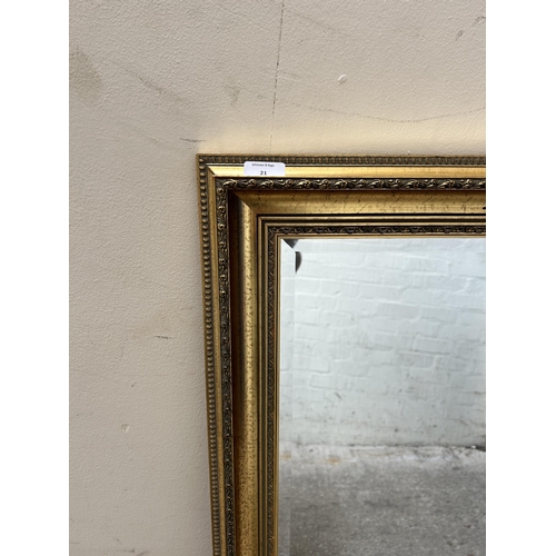 21 - A gilt framed bevelled edge wall mirror - approx. 132cm x 103cm