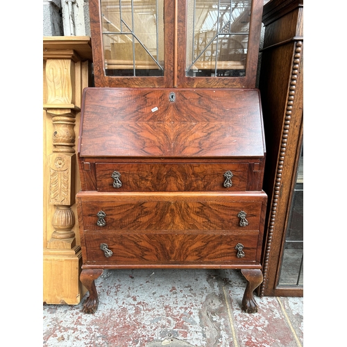 27 - A walnut effect bureau bookcase with two leaded glass doors, fall front, three drawers and ball and ... 