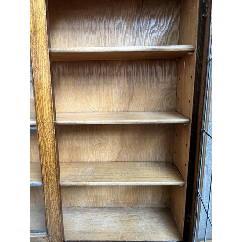 35 - An early 20th century carved oak bureau bookcase with two upper stained and leaded glass doors, fall... 