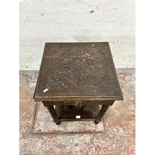 70 - A Victorian carved oak two tier side table with green man design and barley twist supports - approx.... 