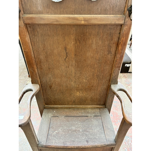 83 - A mid 20th century oak hall stand with lidded seat, central bevelled edge mirror and six coat hooks