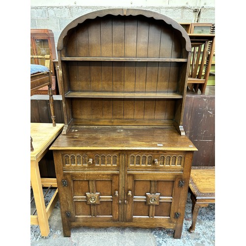 46 - An L. Marcus Ltd carved oak dresser with arched two tier plate rack, two drawers and two cupboard do... 