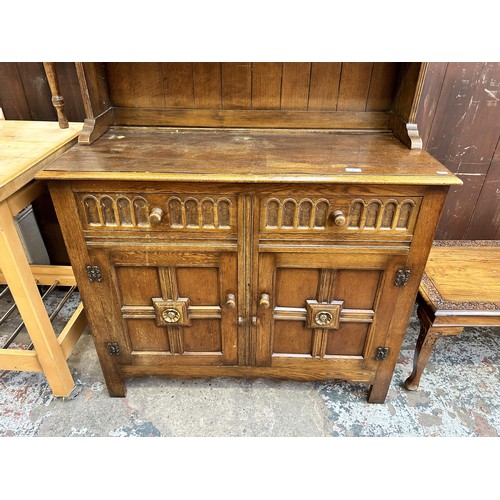 46 - An L. Marcus Ltd carved oak dresser with arched two tier plate rack, two drawers and two cupboard do... 