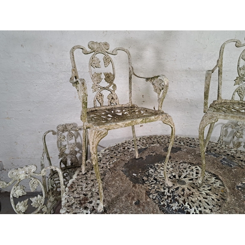 822 - A Victorian style cast metal seven piece garden patio set comprising six chairs and table decorated ... 