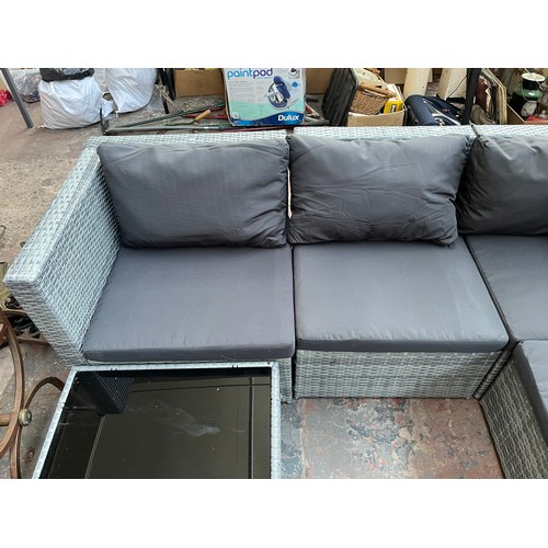 814 - A rattan effect L shaped garden sofa with tempered glass topped side table - approx. 67cm high x 204... 