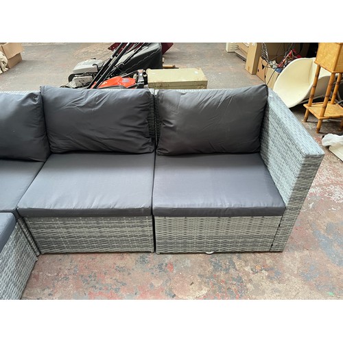 814 - A rattan effect L shaped garden sofa with tempered glass topped side table - approx. 67cm high x 204... 