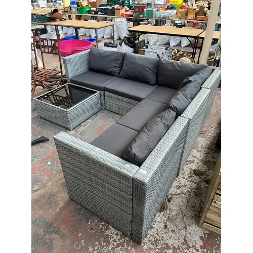 814 - A rattan effect L shaped garden sofa with tempered glass topped side table - approx. 67cm high x 204... 