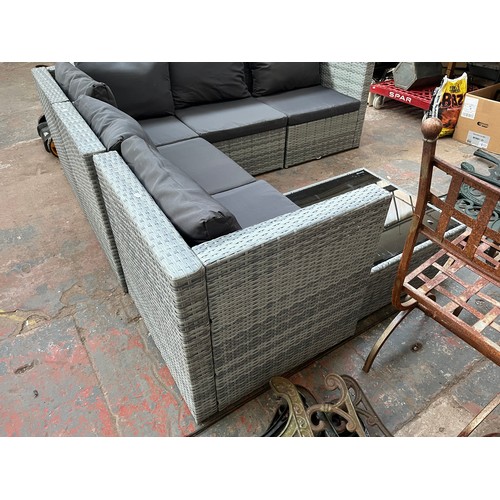 814 - A rattan effect L shaped garden sofa with tempered glass topped side table - approx. 67cm high x 204... 