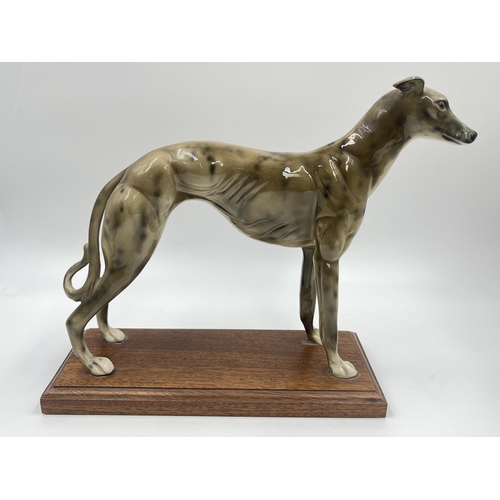 242 - Two ceramic figurines of greyhounds on mahogany plinths - approx. 22cm high x 10cm wide x 23cm long