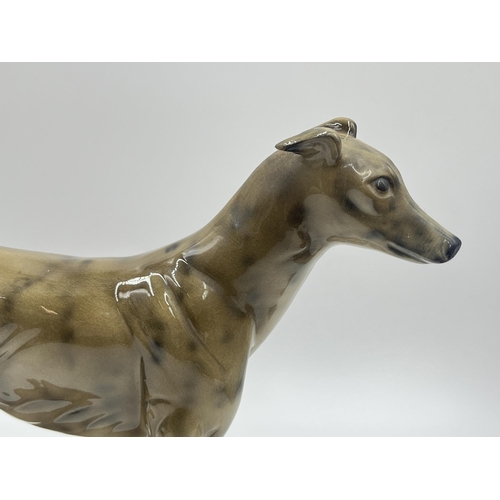 242 - Two ceramic figurines of greyhounds on mahogany plinths - approx. 22cm high x 10cm wide x 23cm long