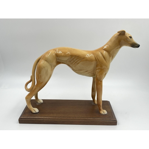 242 - Two ceramic figurines of greyhounds on mahogany plinths - approx. 22cm high x 10cm wide x 23cm long