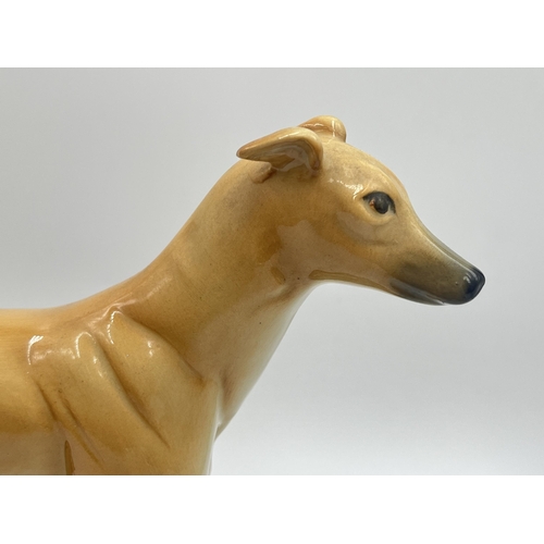 242 - Two ceramic figurines of greyhounds on mahogany plinths - approx. 22cm high x 10cm wide x 23cm long