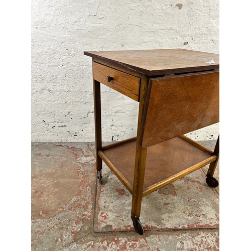 130 - A mid 20th century oak drop leaf two tier tea trolley with single drawer and castors