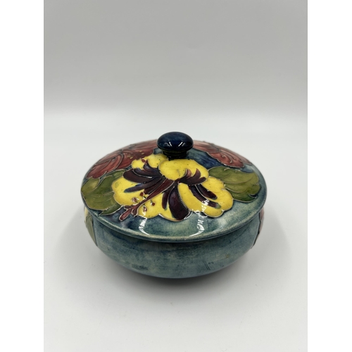 304 - A Moorcroft Hibiscus pattern circular lidded trinket box - approx. 12cm diameter