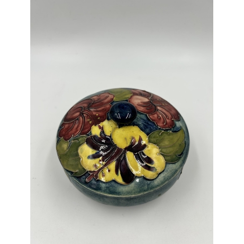 304 - A Moorcroft Hibiscus pattern circular lidded trinket box - approx. 12cm diameter