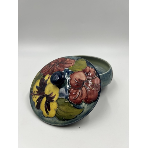 304 - A Moorcroft Hibiscus pattern circular lidded trinket box - approx. 12cm diameter