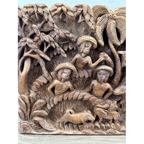 517 - A heavily carved hardwood plaque of a tribal scene - approx. 26cm high x 45cm wide