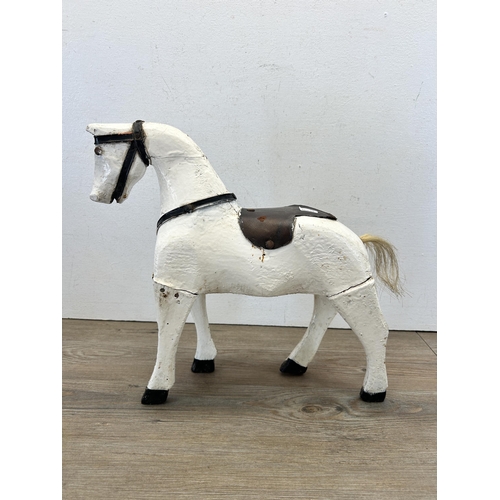 562 - An early 20th century white and black painted hardwood horse figurine - approx. 36cm high x 40cm lon... 