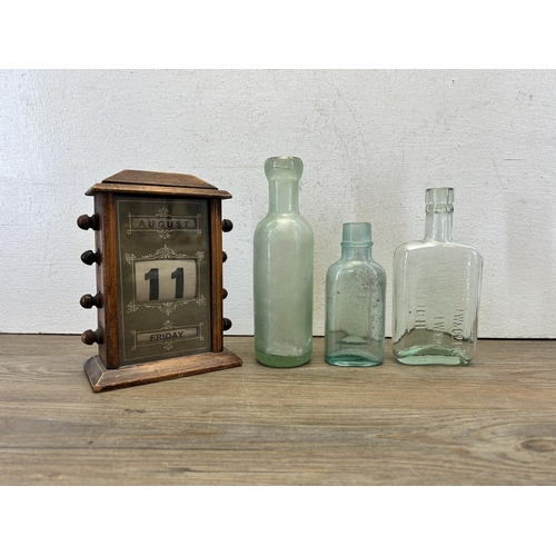 575 - Four items, one wooden cased perpetual desk calendar and three glass bottles