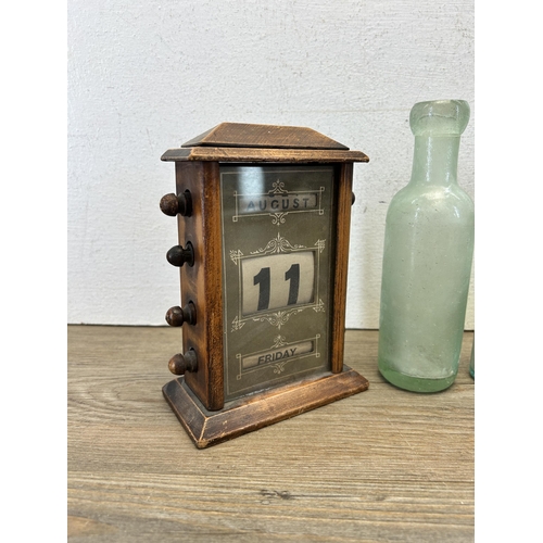 575 - Four items, one wooden cased perpetual desk calendar and three glass bottles