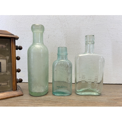 575 - Four items, one wooden cased perpetual desk calendar and three glass bottles