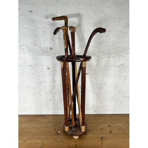 595 - An oak stick stand containing five walking canes