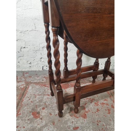 110 - An oak drop leaf gate leg oval occasional table on barley twist supports