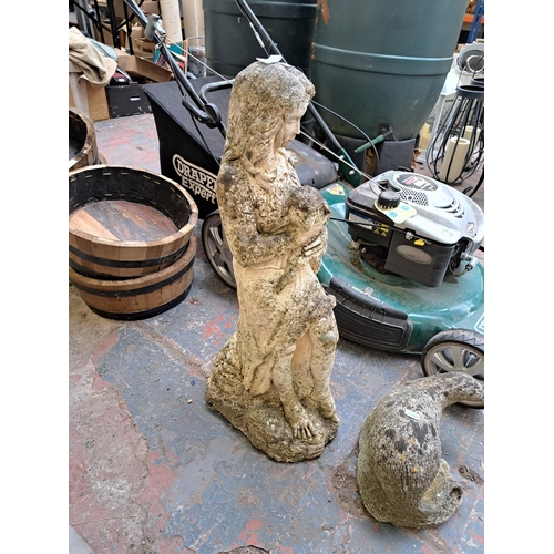 800 - Two cast stone garden ornaments, one statuette of a lady and lamb and one otter figurine