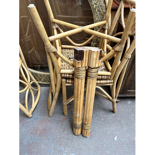 132 - A wicker and cane circular dining table with glass top and four dining chairs