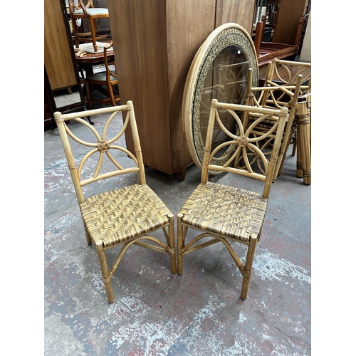 132 - A wicker and cane circular dining table with glass top and four dining chairs