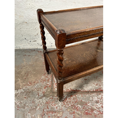 156 - A mid 20th century oak barley twist two tier tea trolley with beaded decoration