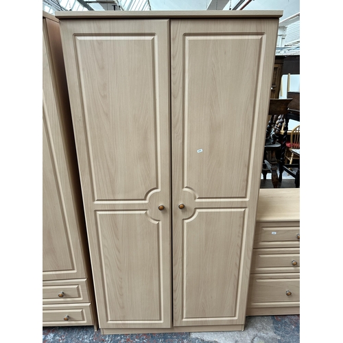 174 - A modern beech effect five piece bedroom suite comprising three chests of drawers and two double war... 