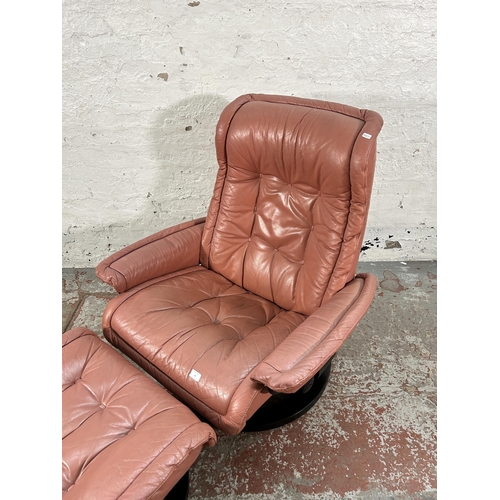 18 - An Ekornes Stressless light tan leather and black painted swivel reclining armchair and footstool