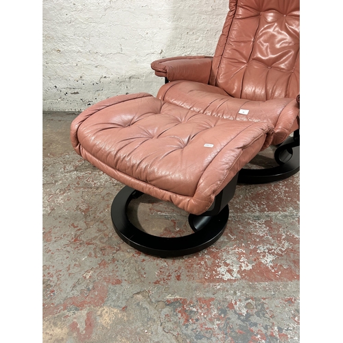 18 - An Ekornes Stressless light tan leather and black painted swivel reclining armchair and footstool