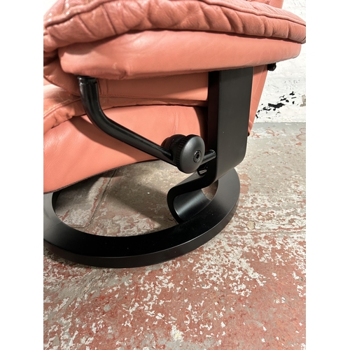 18 - An Ekornes Stressless light tan leather and black painted swivel reclining armchair and footstool