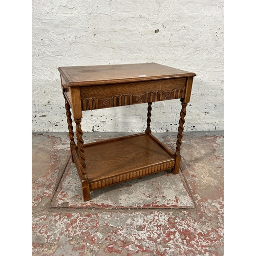 74 - A carved oak two tier side table on barley twist supports