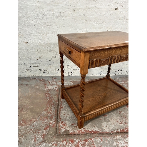 74 - A carved oak two tier side table on barley twist supports