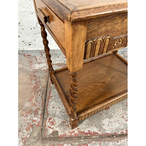 74 - A carved oak two tier side table on barley twist supports